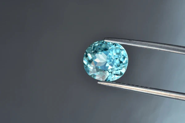 A Blue Zircon held by a tweezer