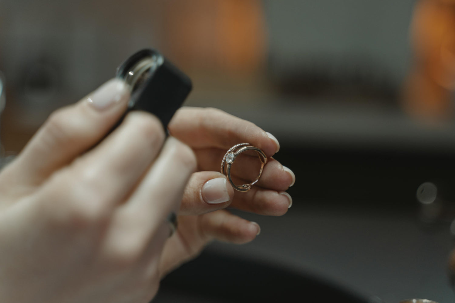 An individual examining a diamond ring through a gemstone loupe