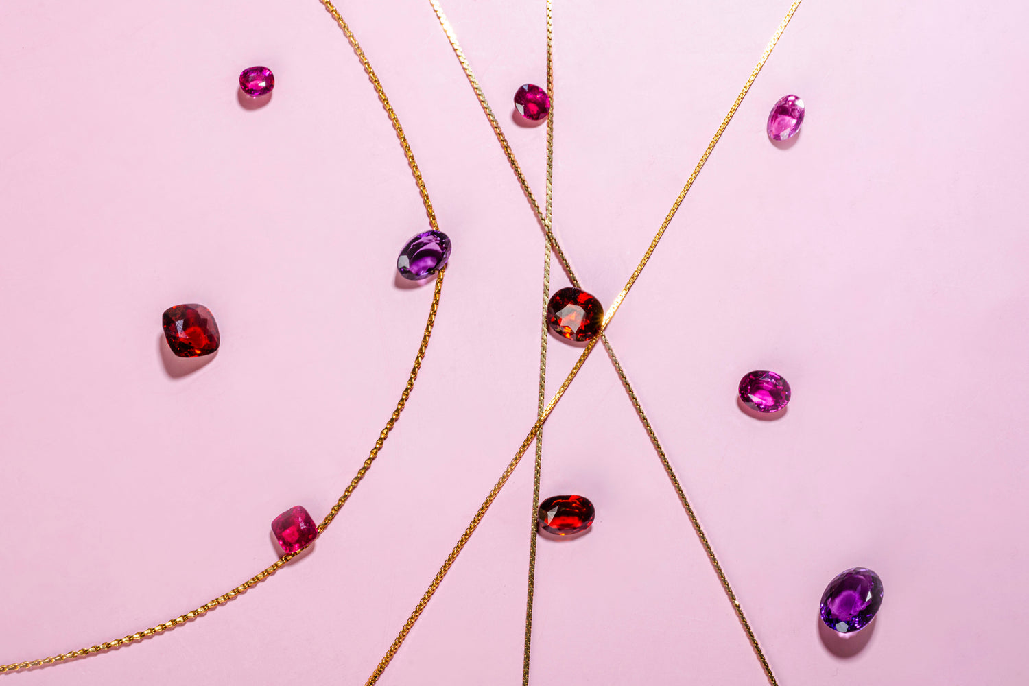 gemstones and gold chains on a pink background