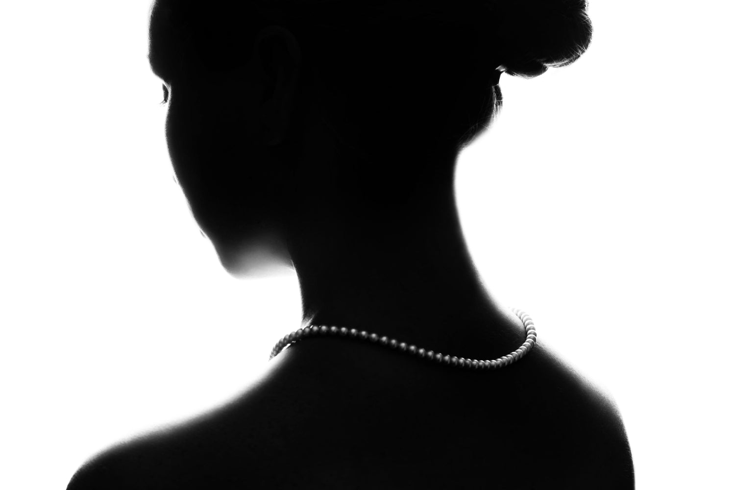 silhouette of a woman wearing a pearl necklace.